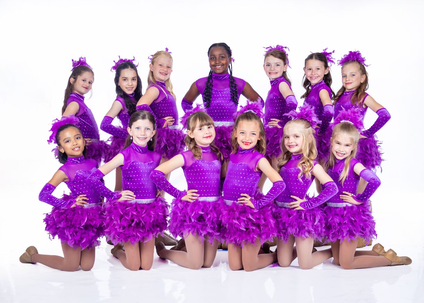 Dance Makers dancers in purple feathered costumes posing as a group